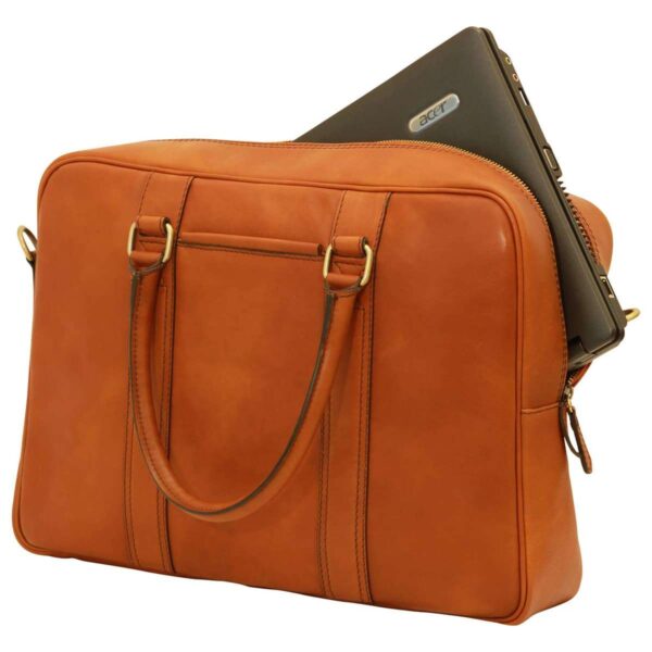 A cognac-colored leather laptop bag shown at an angle, with a dark grey Acer laptop partially inserted into the main zippered compartment. The bag features two slim top handles with brass-tone hardware and vertical leather trim detailing on the front.