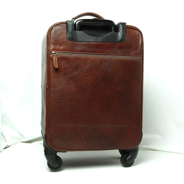 A rear view of the **brown leather carry-on suitcase** standing upright. The image shows the retracted **telescopic handle** housing, a horizontal **zippered back pocket**, and the four spinner wheels, set against a white background.