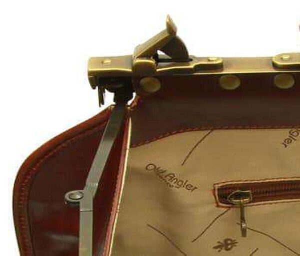 Close-up detail of an open leather doctor bag showing the brass frame hinge, metal clasp, and branded interior lining with a zippered pocket