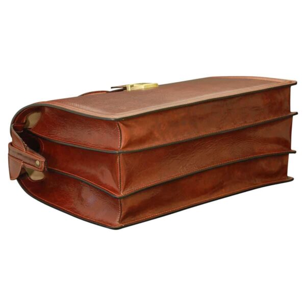 A bottom-side view of a cognac-colored leather doctor-style briefcase, showing its three distinct gusseted compartments and reinforced base construction.