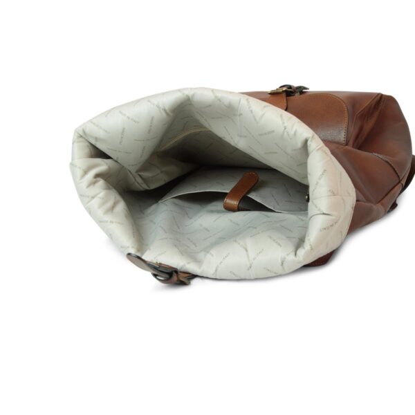 An open view of a brown leather backpack's interior, showing a spacious main compartment lined with a cream-colored fabric patterned with the "MADE IN ITALY" logo. The interior includes a dedicated pocket with a leather strap closure and a zippered side compartment for organization.