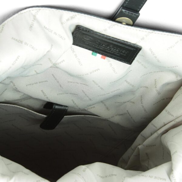 Close-up of the interior of a leather bag featuring light-colored fabric lining patterned with the words "MADE IN ITALY" and a black leather brand patch.