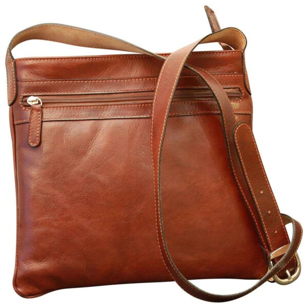 A front-facing view of a chestnut brown leather crossbody bag, featuring a horizontal zippered pocket, tonal stitching, and a long adjustable leather strap with a metallic buckle.