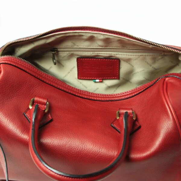 A top-down, close-up view of an open red leather handbag, showing the beige interior lining patterned with "MADE IN ITALY" text, a zippered inner pocket, and a red leather brand label.