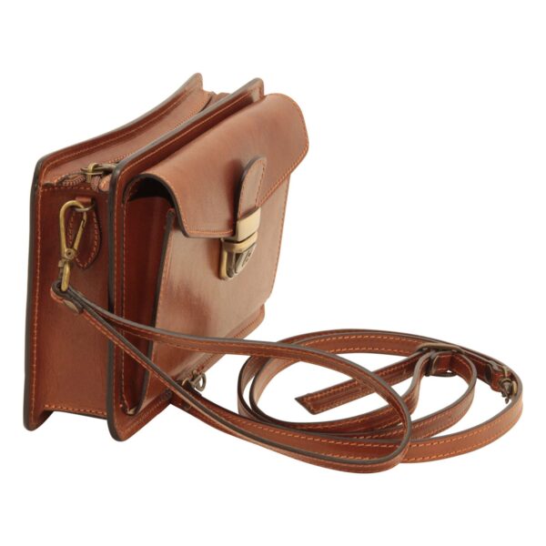 Side view of a tan leather crossbody bag with an open front compartment, brass tuck lock, and thin adjustable strap
