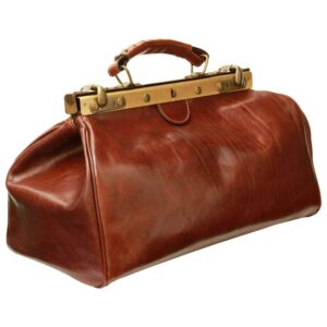 A three-quarter perspective shot of a vintage-style brown leather doctor's bag, highlighting its structured silhouette, brass-toned metal frame with a keyhole closure, and a reinforced leather top handle.
