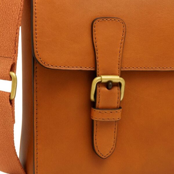 A close-up view of the front flap of a tan leather messenger bag, focusing on the brass buckle closure and a vertical leather strap with detailed stitching.