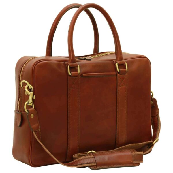 A three-quarter view of a cognac-colored leather briefcase, featuring rounded top handles, a main zippered compartment with gold-tone hardware, and a matching detachable leather shoulder strap with a padded section.