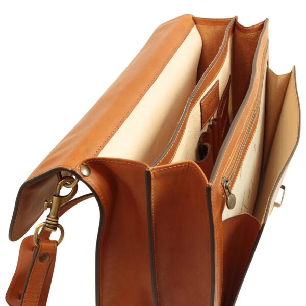 An open, multi-compartment tan leather briefcase shown from a high-angle view to reveal its interior. The bag features cream-colored lining, several dividers including a zippered pocket, pen holders, and an organizational panel. It is equipped with antique-style brass hardware and a matching leather shoulder strap, set against a white background.