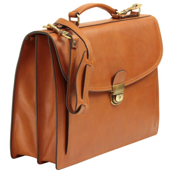 Το Gemini είπε A tan leather briefcase with a top handle and a detachable shoulder strap, featuring a front flap with a brass push-lock closure and a structured, multi-compartment design.