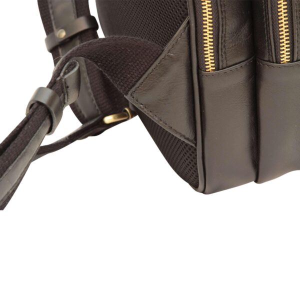 Close-up view of the bottom corner and padded shoulder strap attachment of a dark brown leather backpack