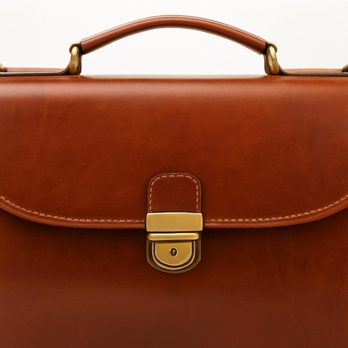 il_fullxfull.6888671779_p3lp.jpg Close-up detail of tan leather briefcase featuring a brass tuck lock fastener and a sturdy top carry handle