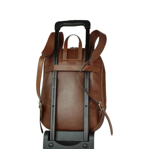 Back view of tan brown leather backpack attached to a telescopic luggage handle via its trolley strap
