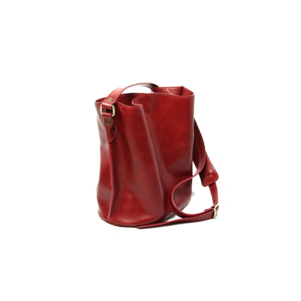A three-quarter studio view of a red leather bucket bag on a white background, displaying its supple texture, reinforced side seams, and an adjustable shoulder strap with a padded section.