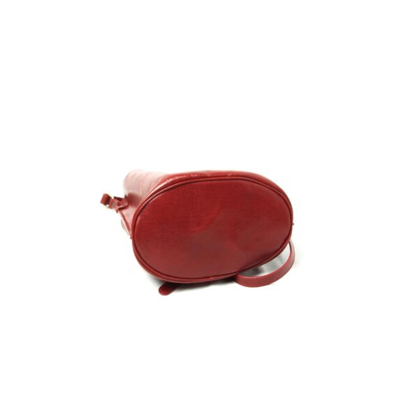 A high-angle studio shot showcasing the oval-shaped base of a red leather bucket bag, isolated on a clean white background.