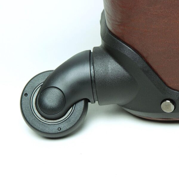 A close-up shot of a single black **multidirectional spinner wheel** attached to the base of the brown leather suitcase. The image highlights the sturdy plastic housing and the smooth, rotating design of the wheel, set against a white background.