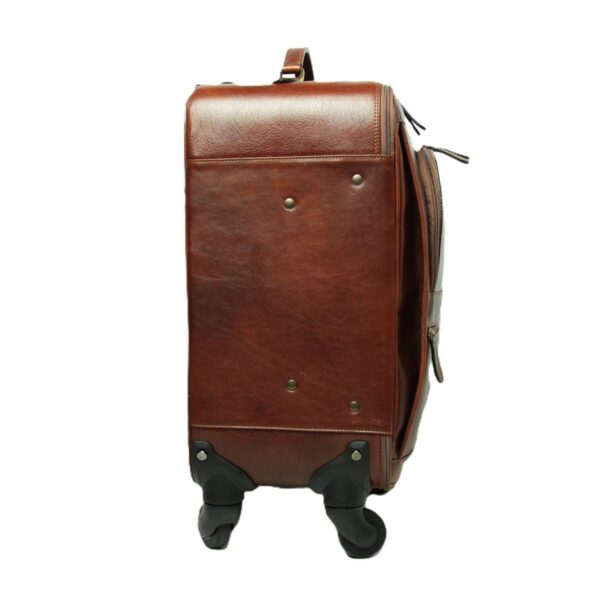 A side profile view of a **brown leather carry-on suitcase** standing upright on its four spinner wheels. The image showcases the smooth leather side panel with reinforced metal studs and the top carrying handle, set against a clean white background.