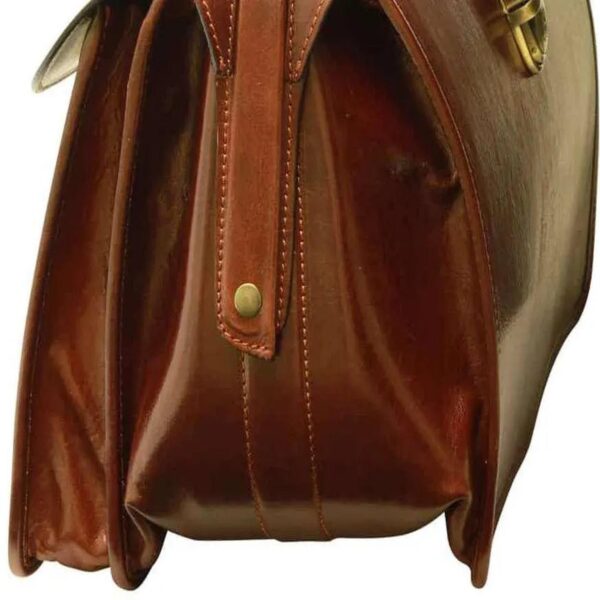 Close-up of a side profile of a vintage-style, cognac-colored leather briefcase featuring accordion-style expandable compartments, visible stitching, and a brass stud detail on a vertical strap.