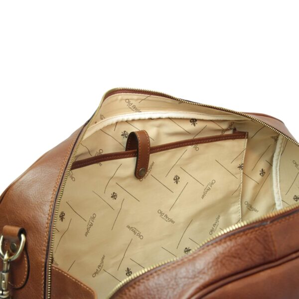 Interior view of a brown leather duffle bag showing a cream lining with Old Angler brand pattern, an inner zipper pocket with leather pull tab, and gold-tone zipper detail along the opening