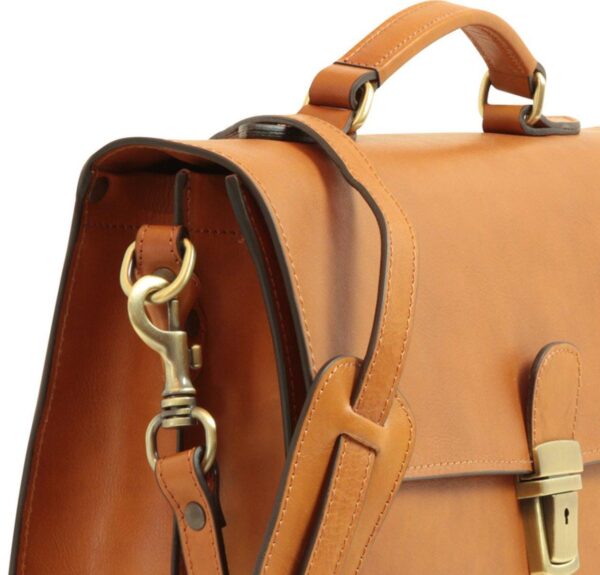 lose-up of a tan leather briefcase featuring a reinforced top handle, adjustable shoulder strap with brass swivel lobster clasp, and a gold-tone metallic push-lock closure with a keyhole.