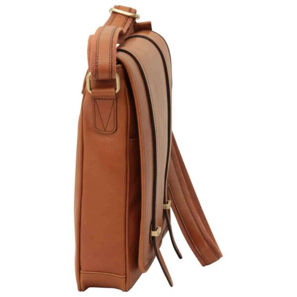 A side-profile view of a tan leather messenger bag, highlighting its slim vertical design, the layered front flap with dark trim, and the reinforced stitching where the canvas shoulder strap meets the brass hardware.