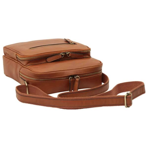 A high-angle view of a tan leather messenger bag lying flat, showcasing its tiered zippered compartments and an adjustable canvas-and-leather shoulder strap.