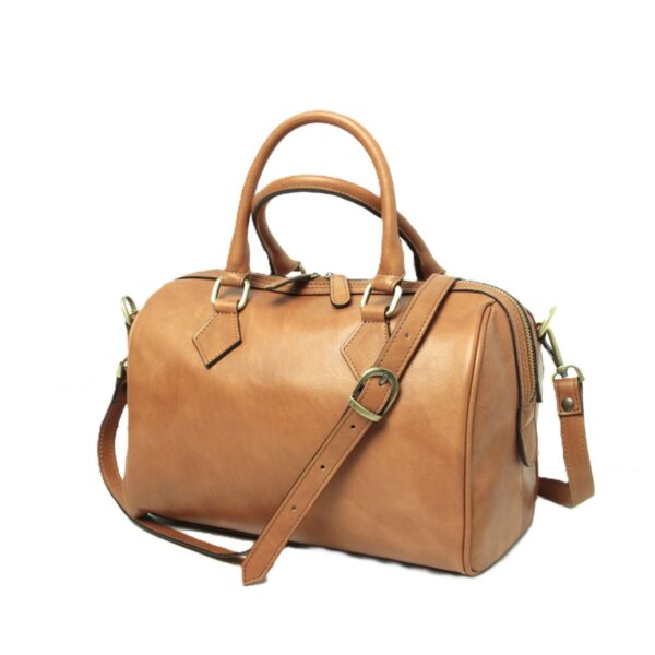 A honey-colored tan leather Boston bag with a smooth matte finish, featuring rolled top handles and a long, adjustable shoulder strap with brass hardware. The bag is shown at a slight angle on a white background, highlighting its structured barrel shape, double-zippered closure, and diamond-shaped leather accents.