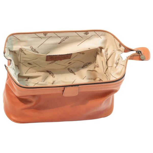 Interior view of an open tan leather toiletry bag, showcasing a wide main compartment with branded beige fabric lining. It features an internal slip pocket with a leather logo patch and a top zipper closure with a leather puller.