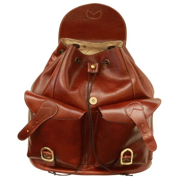 A front-view shot of an open vintage-style brown leather backpack, showcasing its main compartment with a drawstring closure and magnetic snap. The bag features two large front pockets with leather straps and brass buckles, all crafted from rich, polished leather with detailed stitching.
