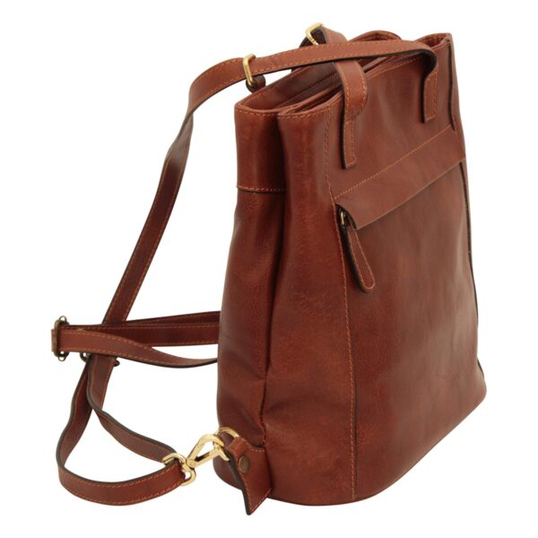 A side-profile view of a cognac-brown leather bag, showing the adjustable straps attached with gold-toned swivel clips, a front zippered pocket with a leather pull tab, and the bag's structured, multi-compartment depth on a white background.