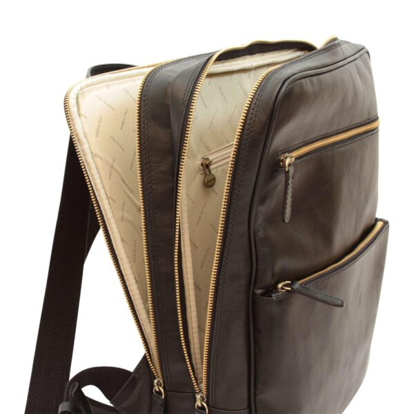 Interior view of an open dark brown leather backpack showing multiple zippered compartments and cream lining